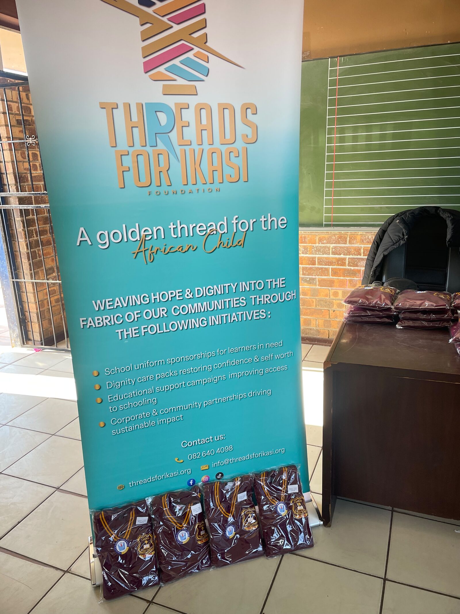 The Threads for iKasi Foundation banner with labelled school jerseys stacked at its base