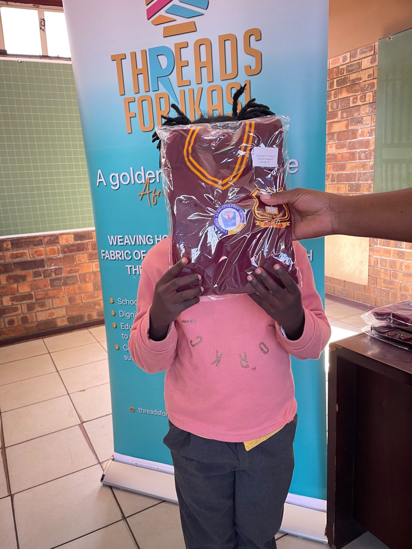 A Thuthuka Primary School learner holding a sealed jersey labelled with their own name, school and grade, 30 July 2026