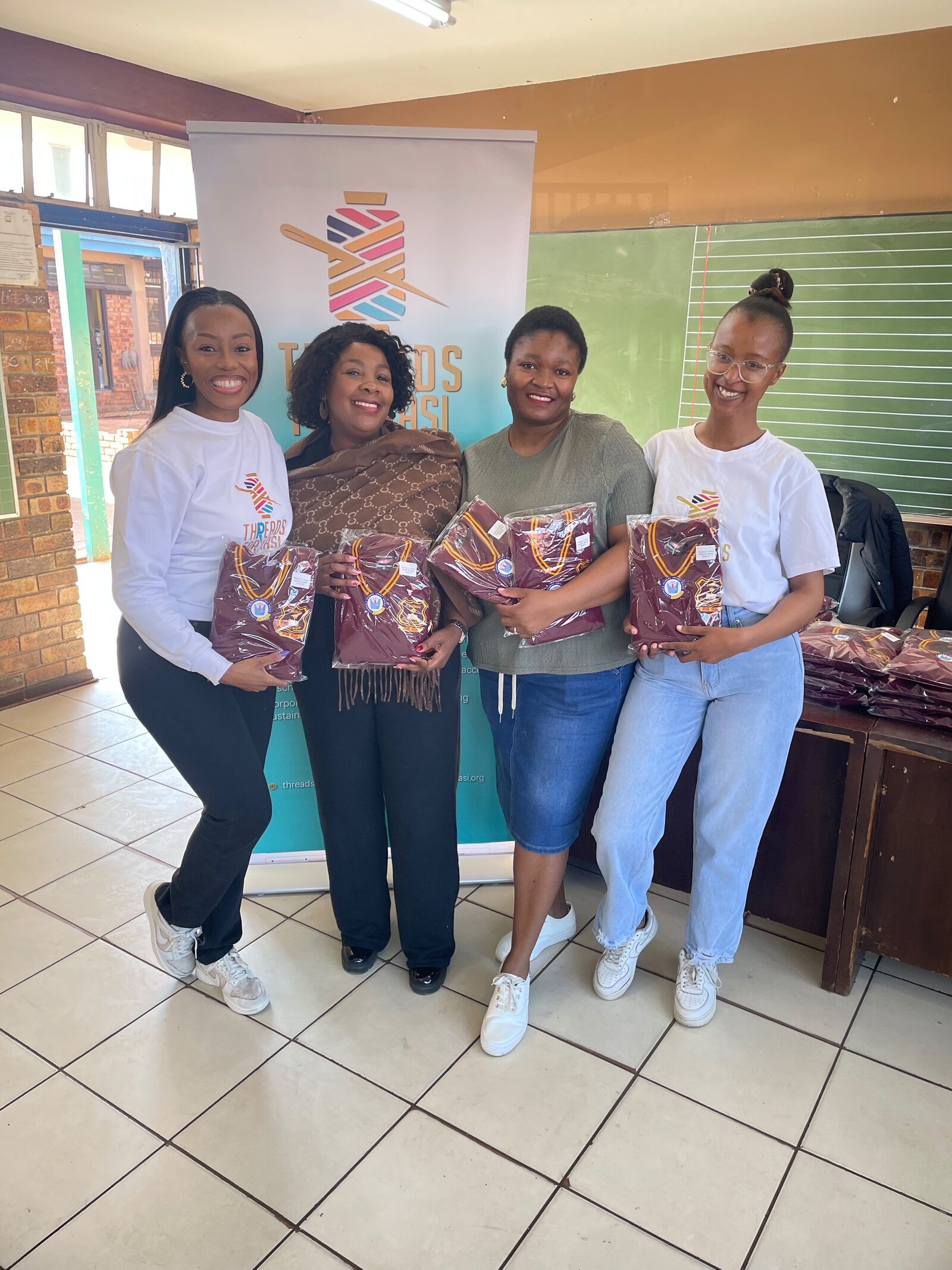 Threads for iKasi Foundation representatives holding Thuthuka Primary School jerseys beside the foundation banner, 30 July 2026