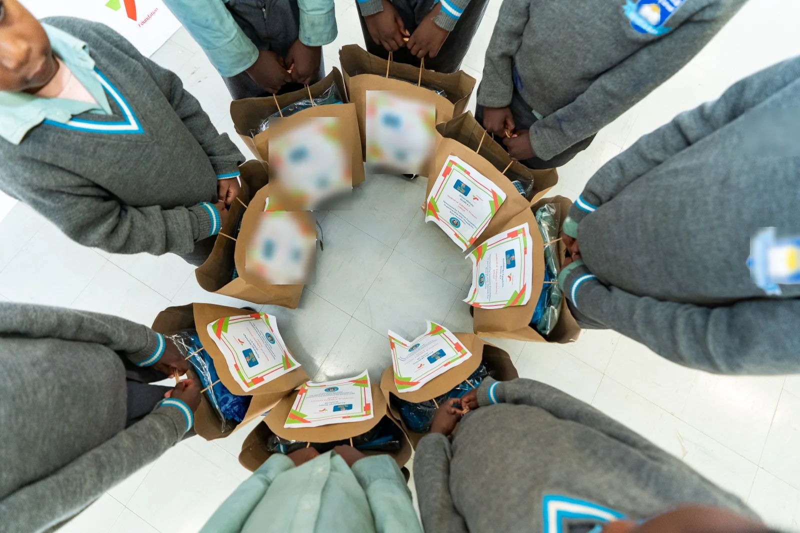 Tshepisa Primary School learners standing in a circle holding the labelled bags containing their new full school uniforms, 6 March 2026