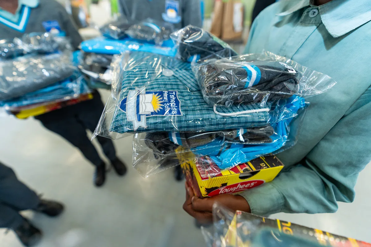 A learner at Tshepisa Primary School holding a full school uniform received at the handover on 6 March 2026