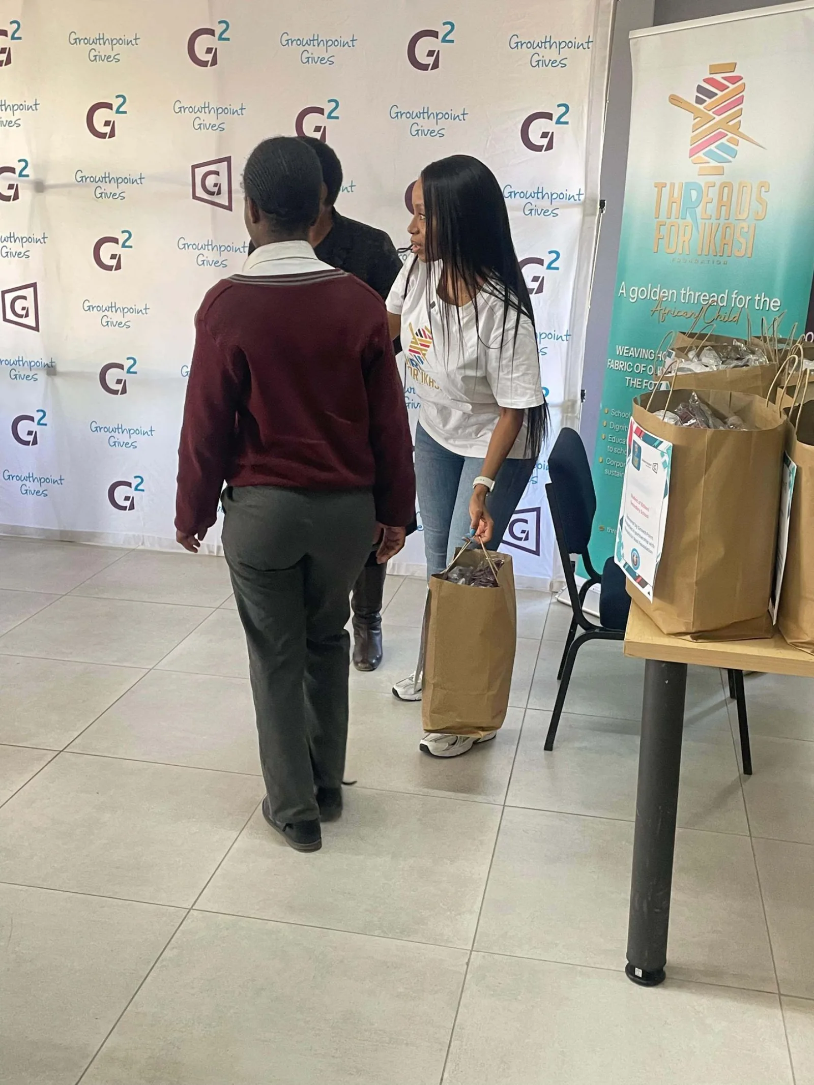 A learner receives their handover bag from a Threads for iKasi volunteer at Zitikeni Secondary School